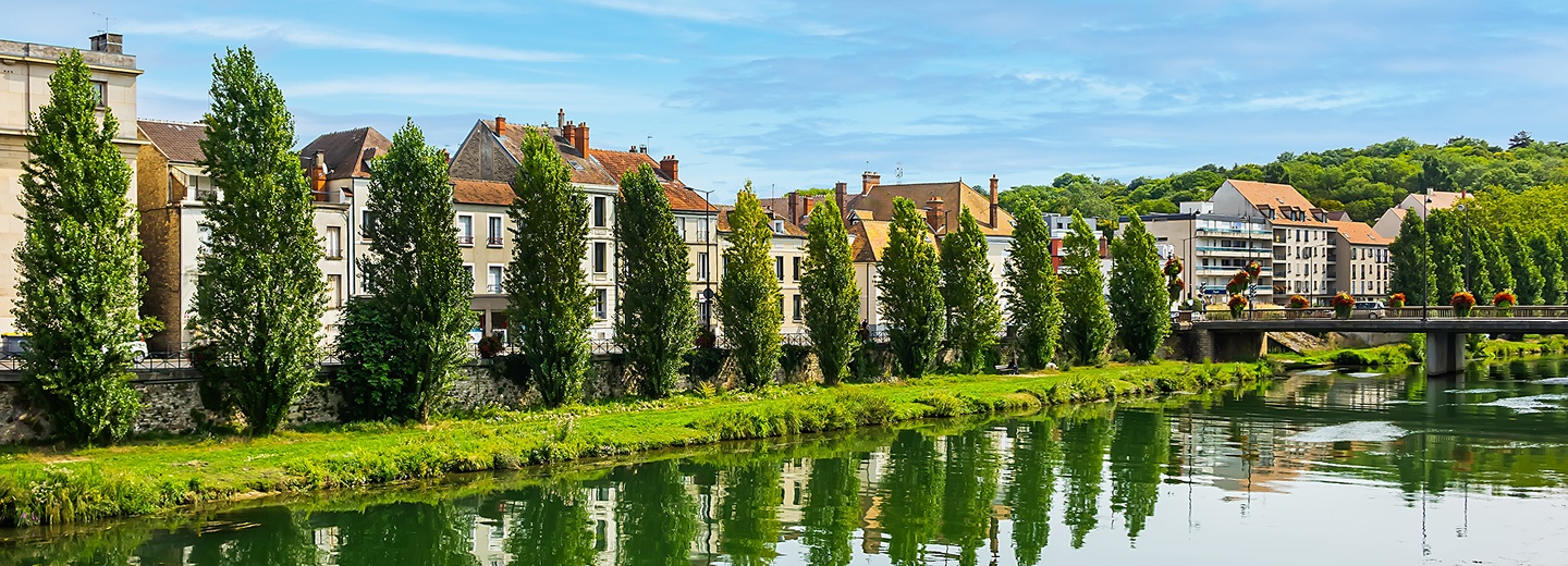 Bord de rivière bordé d'arbres et de maisons dans un village de Seine-et-Marne